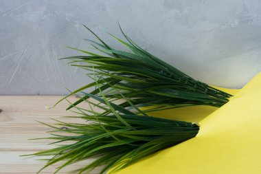 Gri arkaplanda parlak renkli kağıt bulunan yapay yeşil çimenler.