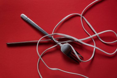 Demir çatallar kırmızı bir zeminde erişte yerine tel ile