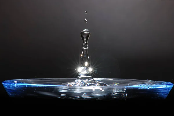 A water droplet splashing back out of a glass of water