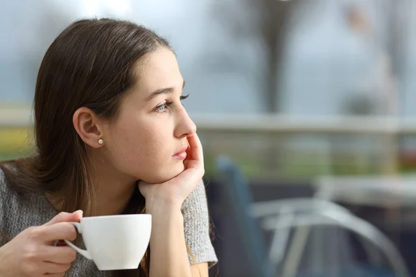 Mujer pensativa mirando hacia otro lado en una cafetería —  Fotos de Stock