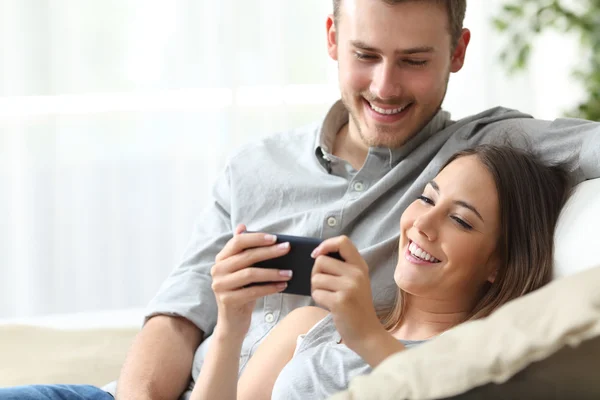 Casal desfrutando de conteúdo de mídia em um telefone inteligente — Fotografia de Stock