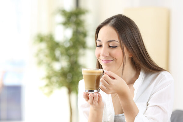 Happy woman enjoying of a cup of coffee with milk