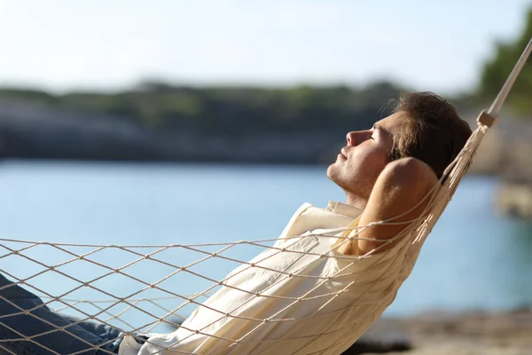 Mann entspannt sich auf einer Hängematte am Strand — Stockfoto