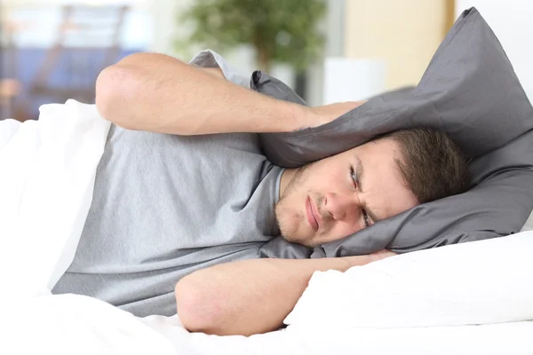 Muž se snaží spát krycí uši pro hluk — Stock fotografie