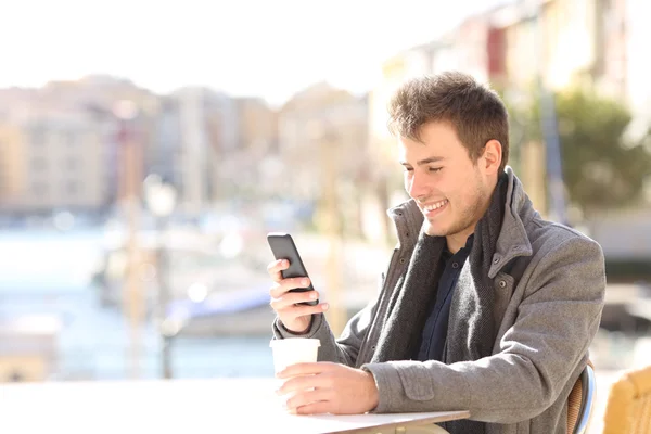 Hombre usando un teléfono inteligente en una cafetería en invierno — Foto de Stock