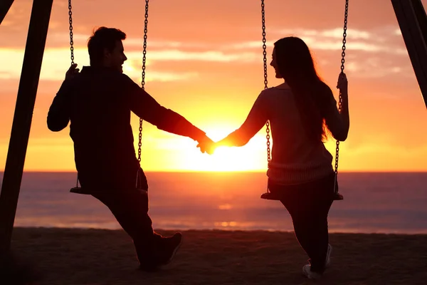 Пара силуэтов держатся за руки и смотрят на восход солнца. — стоковое фото
