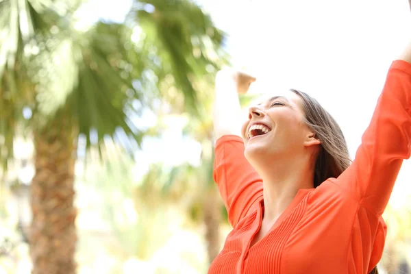 Excited woman raising arms outdoors — Stock Photo, Image