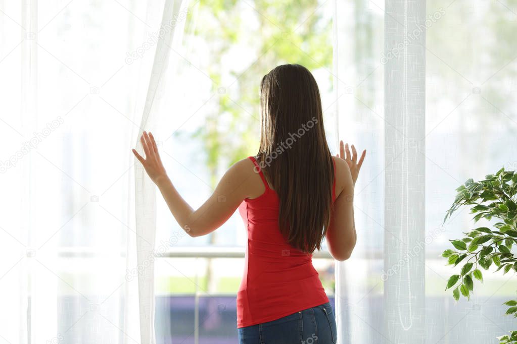Woman looking through a window at home