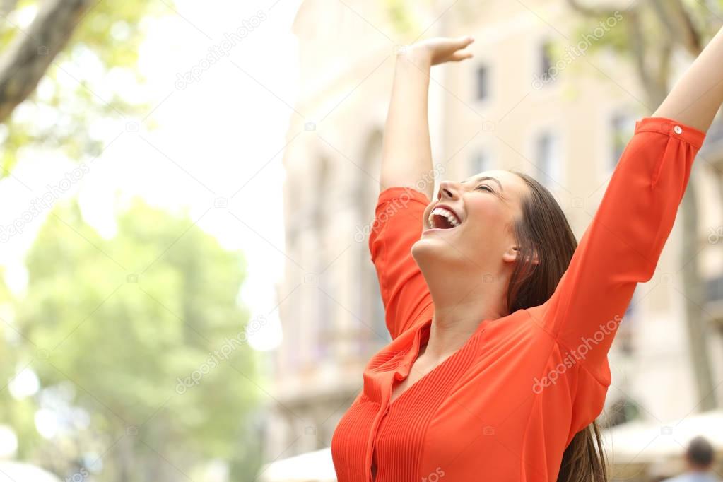 Excited woman raising arms in the street