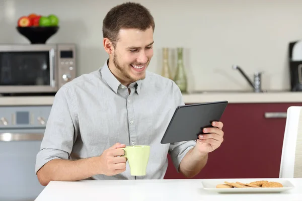 Seorang pria membaca berita di tablet saat sarapan — Stok Foto
