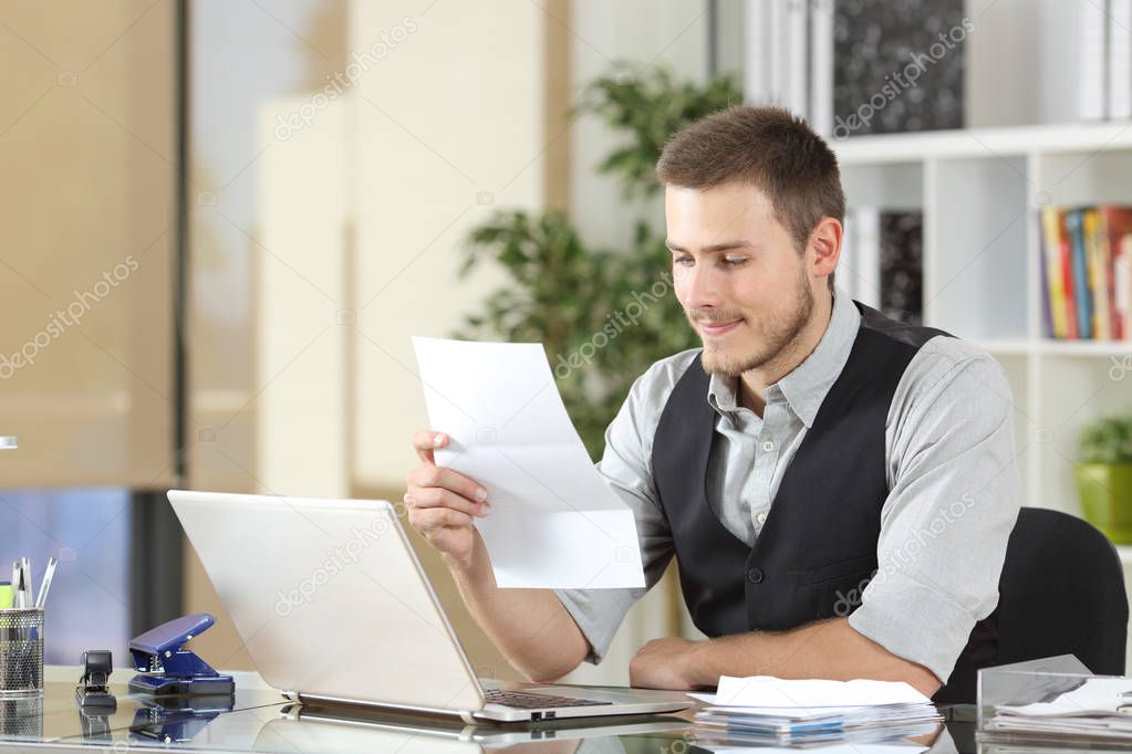 Happy businessman reading a letter at office