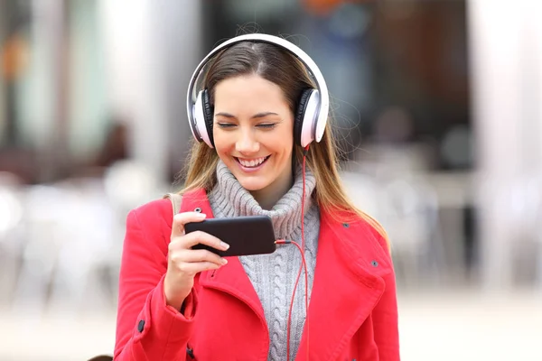 Девушка смотрит видео в смартфоне или слушает музыку — стоковое фото
