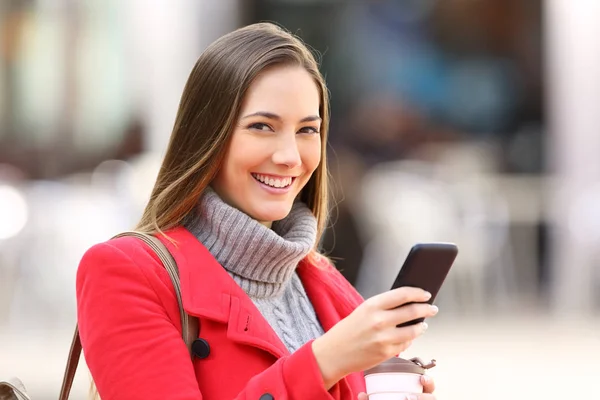 Девушка с телефоном смотрит на тебя зимой — стоковое фото