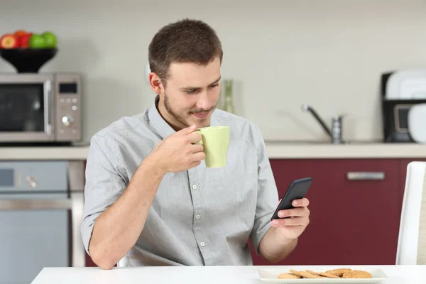 Чоловік читає повідомлення по телефону під час сніданку — стокове фото
