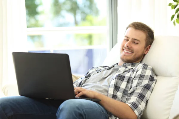 Homem usando um laptop sentado em um sofá — Fotografia de Stock