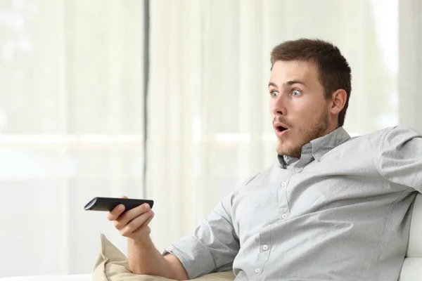 Homem surpreso assistindo TV em casa — Fotografia de Stock