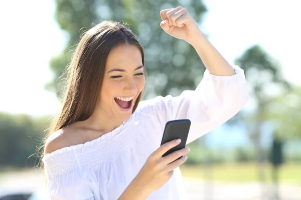 Garota excitada com um telefone celular em um parque — Fotografia de Stock