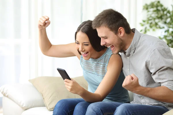 Casal animado assistindo mídia em um telefone celular — Fotografia de Stock