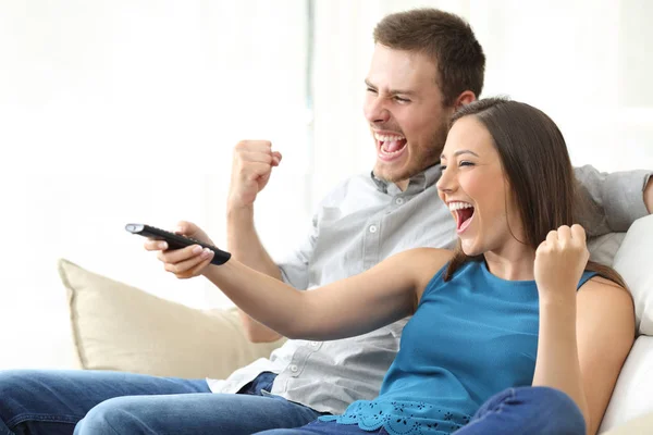 Возбужденная пара смотрит телевизор на диване — стоковое фото