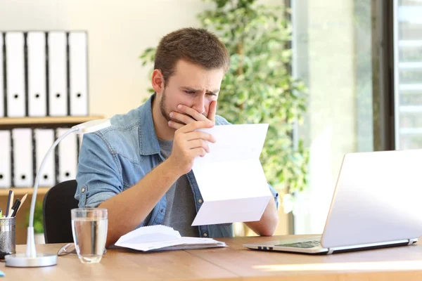 Worried entrepreneur reading a letter — Stockfoto