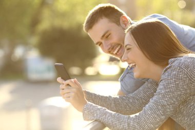 Çift Medya içeriklerinde bir telefon ile gülüyor
