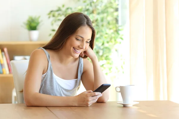 Gadis membaca sms pesan di telepon di rumah — Stok Foto