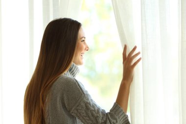 Mutlu kadın bir pencere perdeleri açmayı