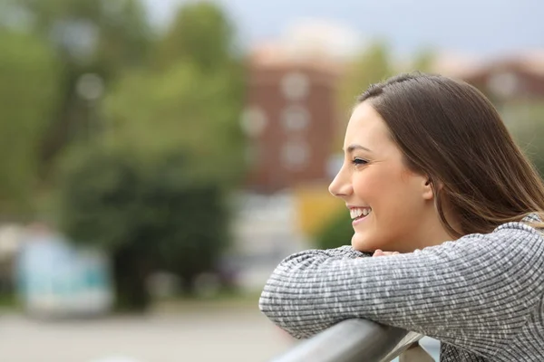 Satisfied girl looking away from a balcony — Stock Photo, Image
