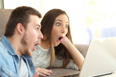 Amazed couple on line with a laptop clipart