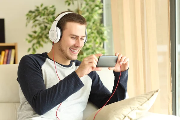 Guy luisteren en kijken naar de media in een smartphone — Stockfoto