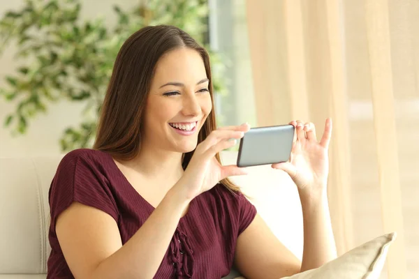 Girl watching videos in a smart phone at home — Stock Photo, Image