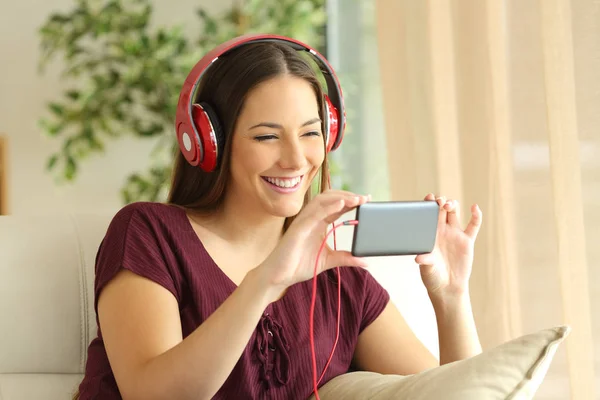 Meisje kijken naar video's in een slimme telefoon met koptelefoon — Stockfoto
