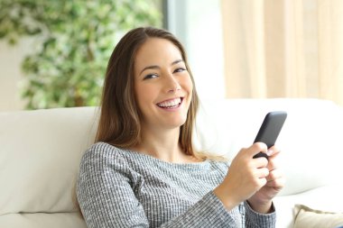 Telefon tutarak ve kameraya bakarak mutlu kız