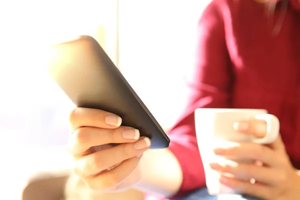 Mãos segurando um telefone celular e xícara de café — Fotografia de Stock