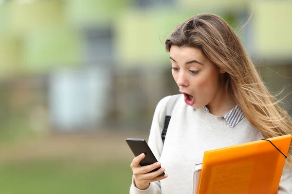 Astonished student receiving news on a smart phone — Stock Photo, Image