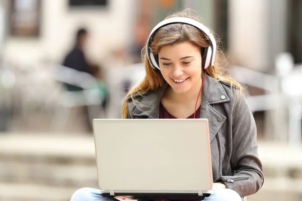 Menina ouvir e baixar música do laptop — Fotografia de Stock