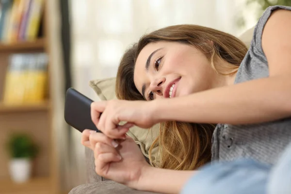 Adolescente mensajes de texto en un teléfono inteligente acostado en el sofá — Foto de Stock