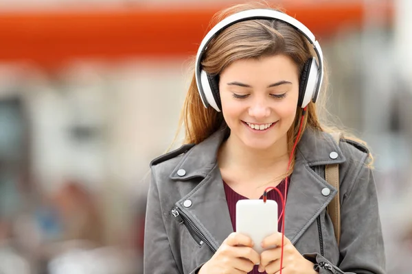 Mulher ouvindo música com fones de ouvido e telefone — Fotografia de Stock