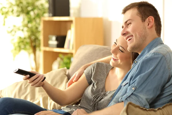 Par titta på tv på en soffa hemma — Stockfoto