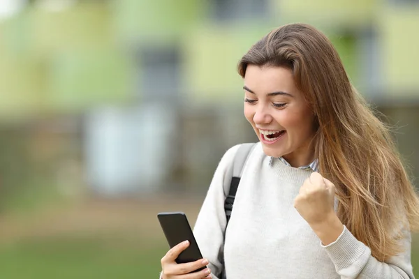 Возбужденный студент читает новости на смартфоне — стоковое фото
