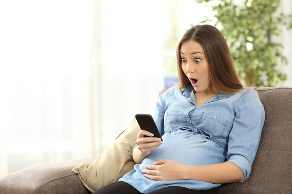 Κατάπληκτος έγκυος γυναίκα ψάχνει στο έξυπνο τηλέφωνο — Φωτογραφία Αρχείου