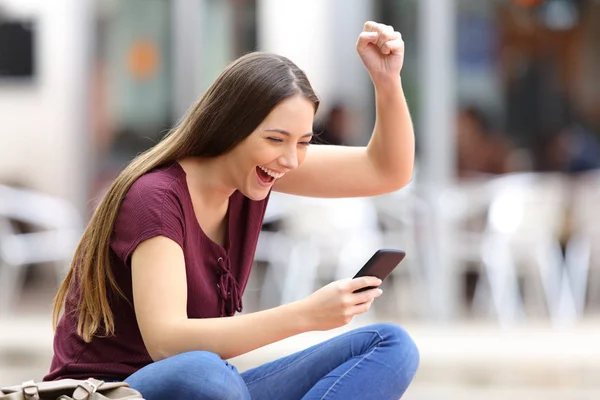 Excited woman with a phone in the street — Stock Photo, Image