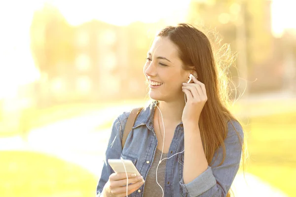 Vrouw luisteren muziek met koptelefoon buitenshuis — Stockfoto