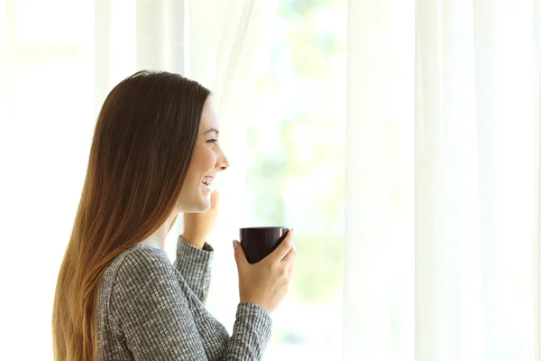 Žena, relaxaci při pohledu přes okno doma — Stock fotografie