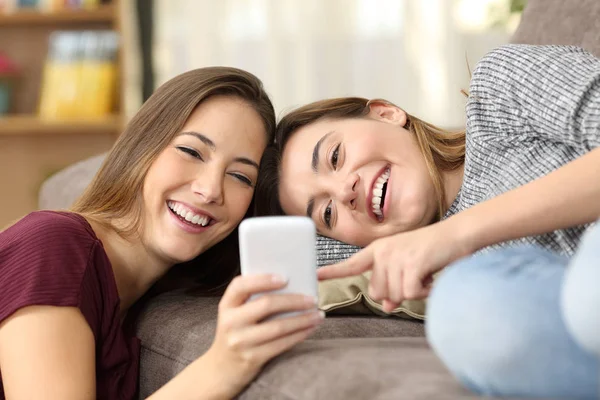 Счастливые соседи по комнате смотрят онлайн контент в телефоне — стоковое фото
