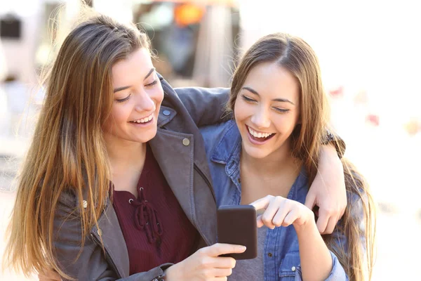 Glada vänner dela en smart telefon — Stockfoto