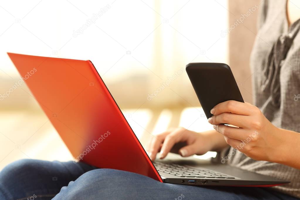 Girl hands using a phone and a red laptop