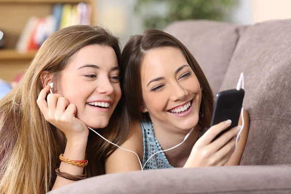 Dos amigos escuchando música en línea desde un teléfono inteligente —  Fotos de Stock