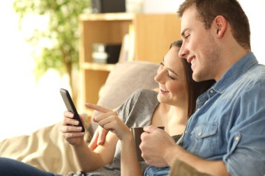 Mutlu çift kanepede bir akıllı telefon kullanma