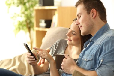 Bir kanepede bir akıllı telefon kontrol çift